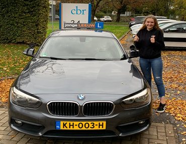 Geslaagde leerling Floor bij de lesauto van Autorijschool JongeLeeuw